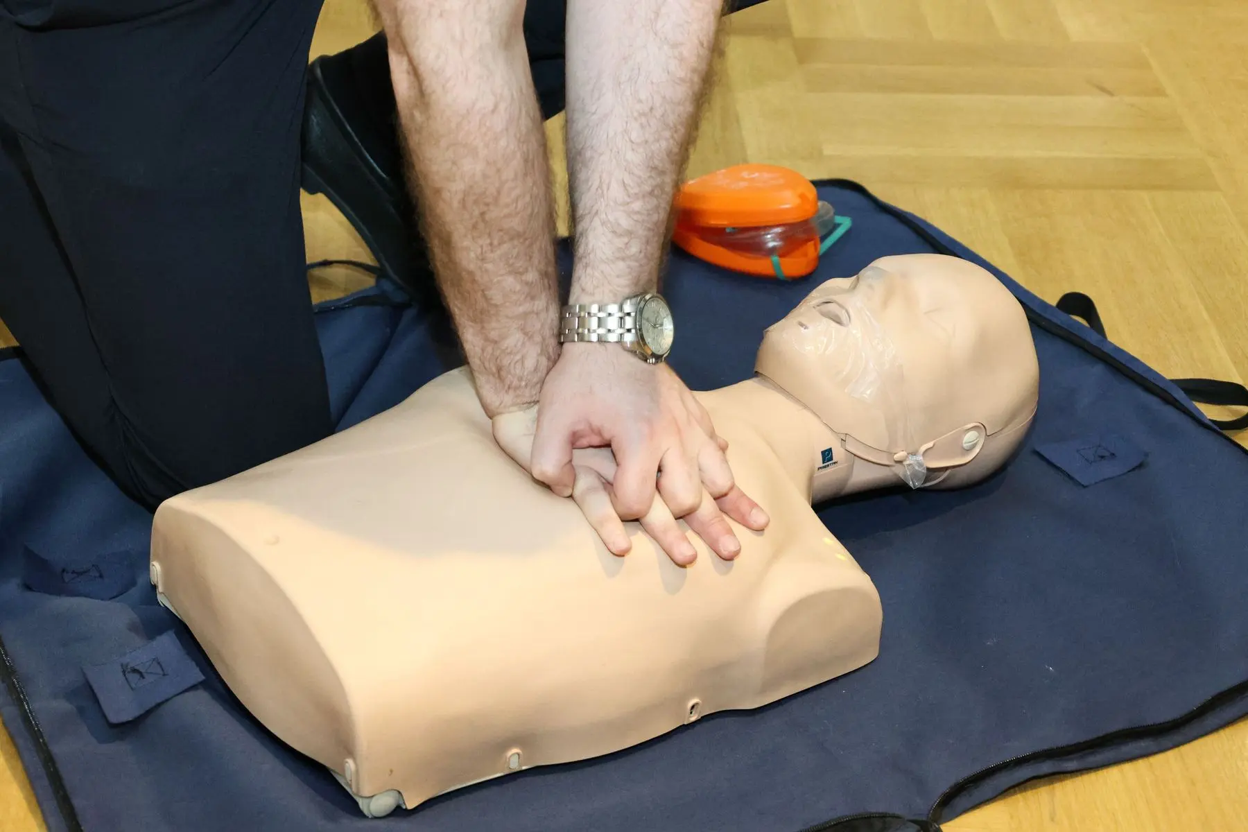 Trainee practising CPR chest compressions on a first-aid mannequin