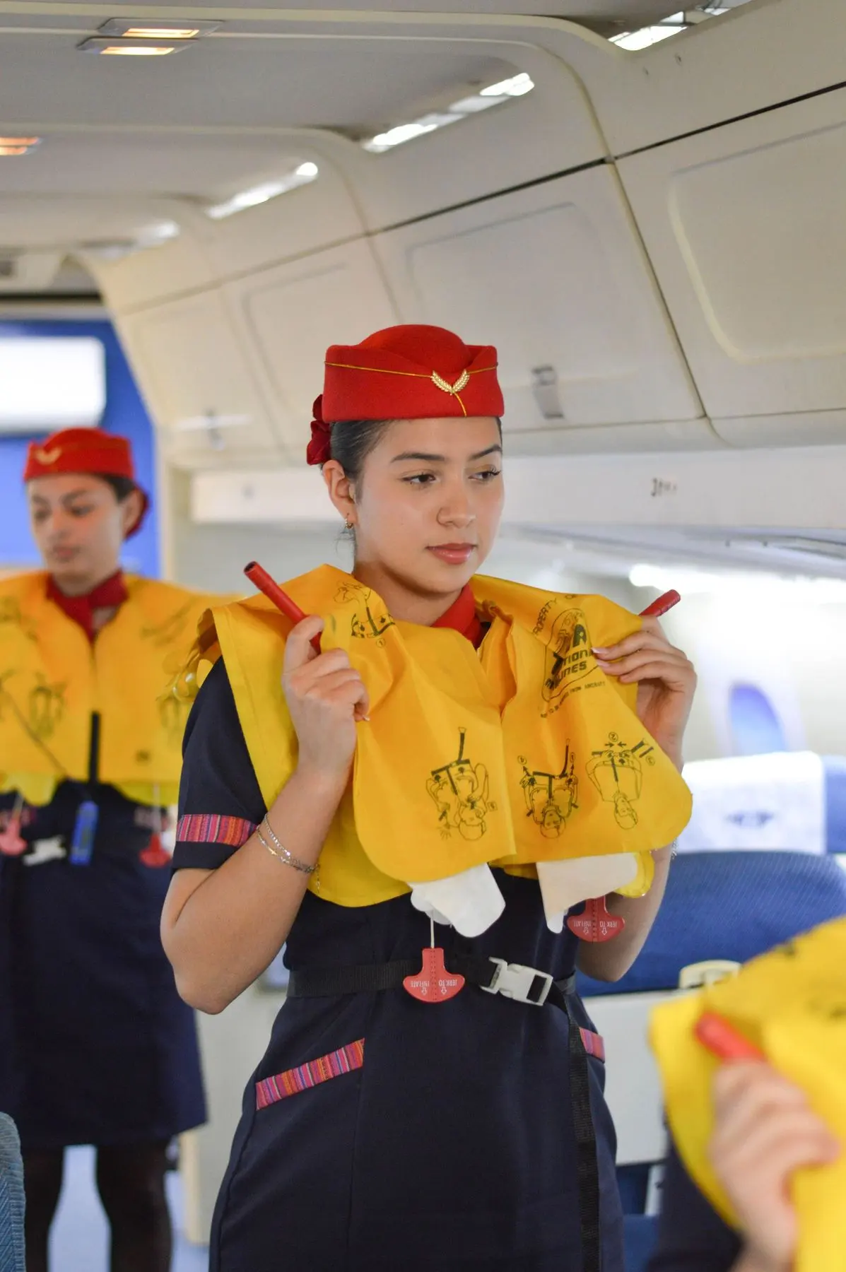 Cabin crew students demonstrating life vests inside a mock aircraft cabin